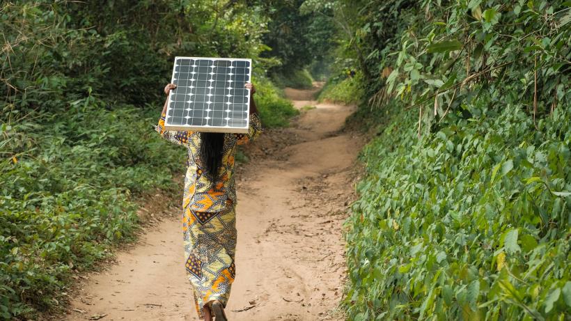 Woman carrying a solar pannel near Yangambi, DRC - Photo by Axel Fassio - CIFOR via Flickr